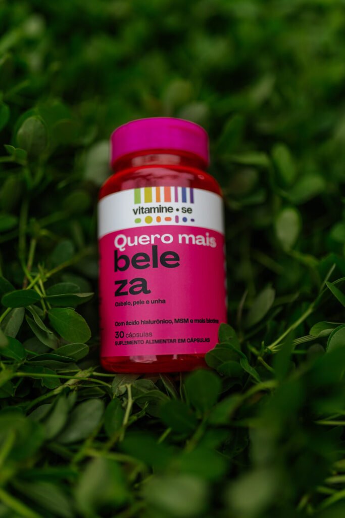 Fotografia de produto do pote Quero Mais Beleza, da linha Vitamine-se da EMS, sobre folhagem no Rio Open 2026