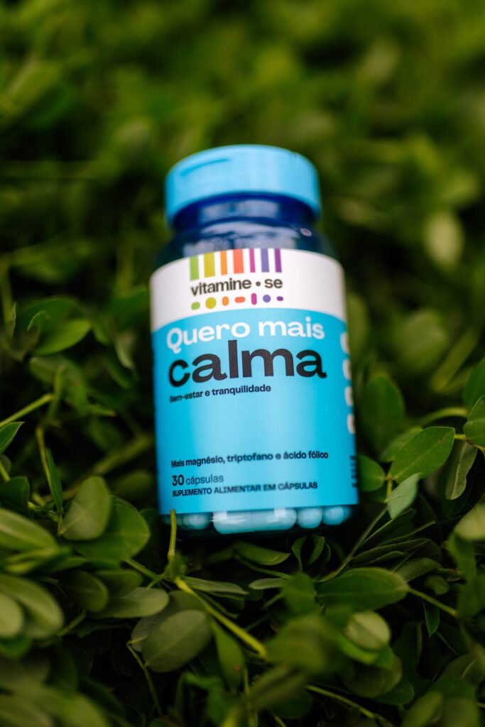 Fotografia de produto do pote Quero Mais Calma, da linha Vitamine-se da EMS, sobre folhagem no Rio Open 2026